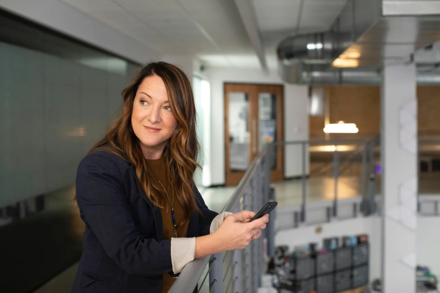 A professional holding a phone in an office atrium